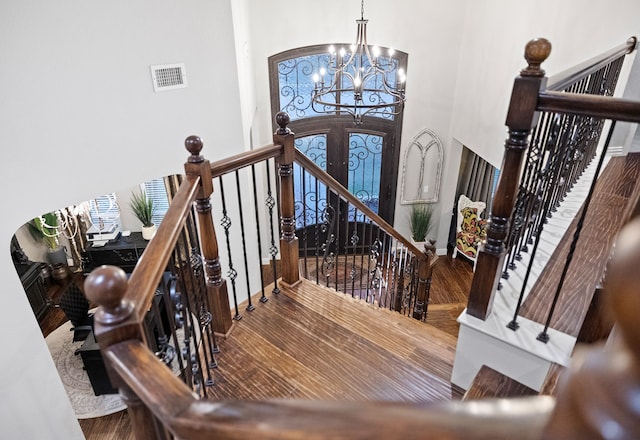 staircase featuring hardwood / wood-style floors and an inviting chandelier