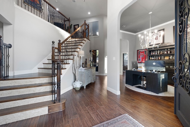 interior space with a notable chandelier, a high ceiling, dark hardwood / wood-style floors, and ornamental molding