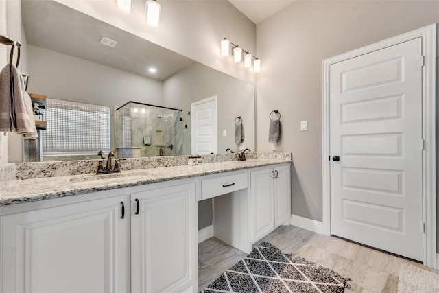 bathroom with a shower with shower door and vanity