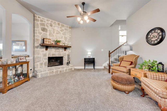 living room featuring ceiling fan, carpet, and a stone fireplace