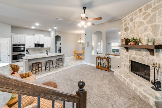 carpeted living room featuring ceiling fan and a fireplace