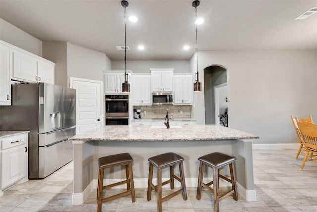 kitchen with white cabinets, pendant lighting, appliances with stainless steel finishes, and a kitchen island with sink