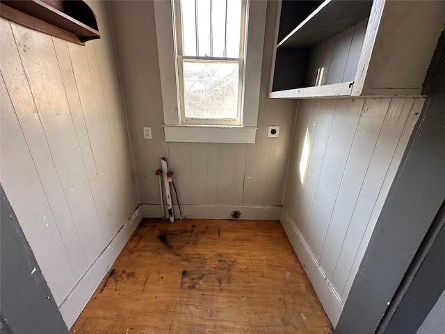 laundry room featuring laundry area, wood walls, hookup for an electric dryer, and light wood-type flooring