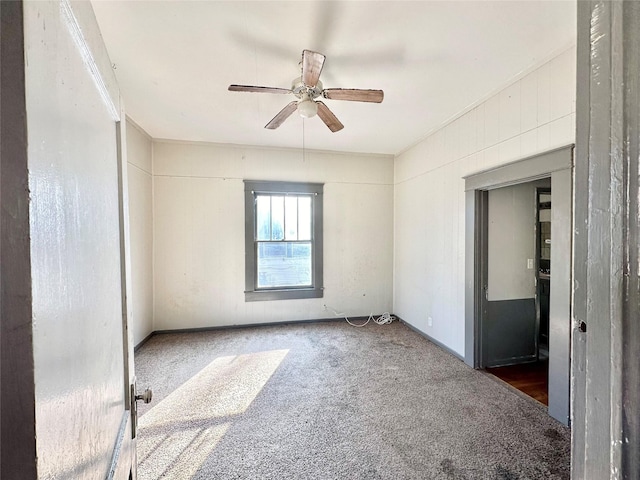 empty room with ceiling fan and dark carpet