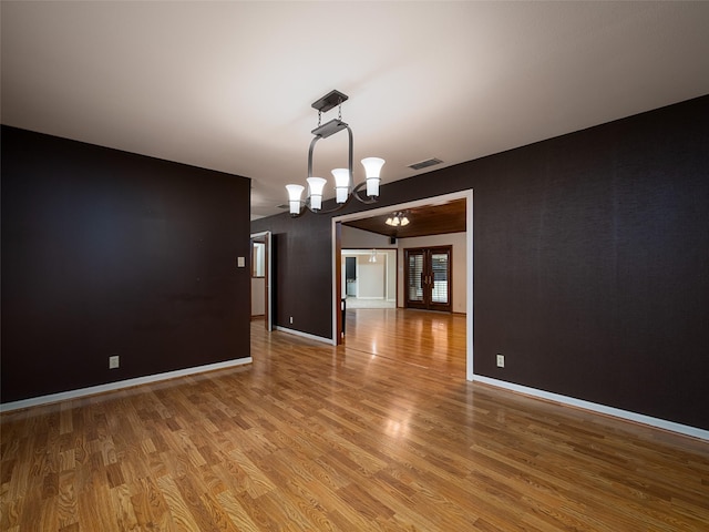 unfurnished dining area featuring a chandelier, hardwood / wood-style floors, and french doors