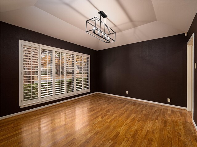 unfurnished dining area featuring a chandelier, hardwood / wood-style floors, and a tray ceiling