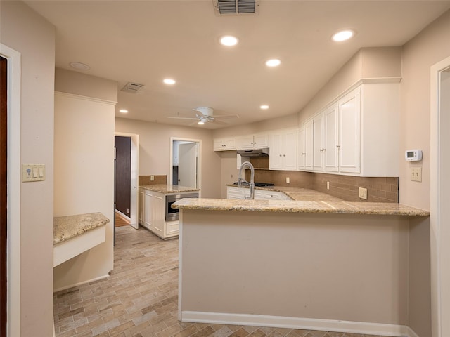 kitchen featuring kitchen peninsula, ceiling fan, white cabinets, and decorative backsplash