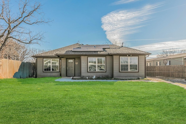 rear view of property with a lawn and solar panels