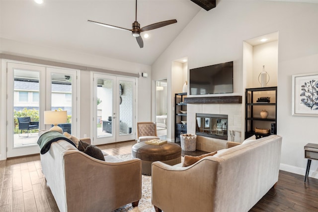 living room with french doors, ceiling fan, a tile fireplace, beamed ceiling, and dark hardwood / wood-style floors