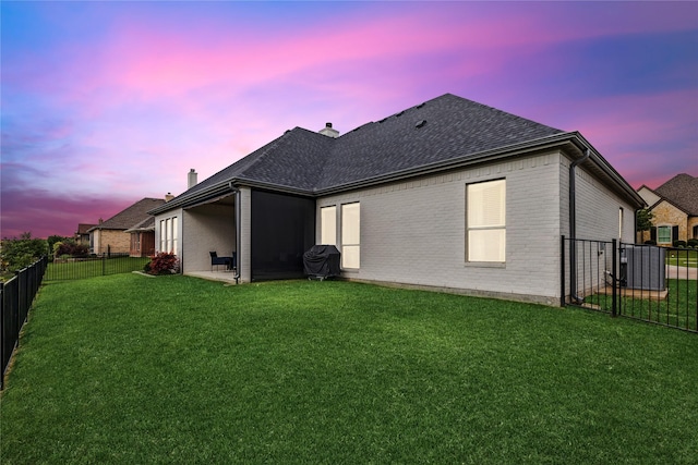 back house at dusk featuring a yard and a patio