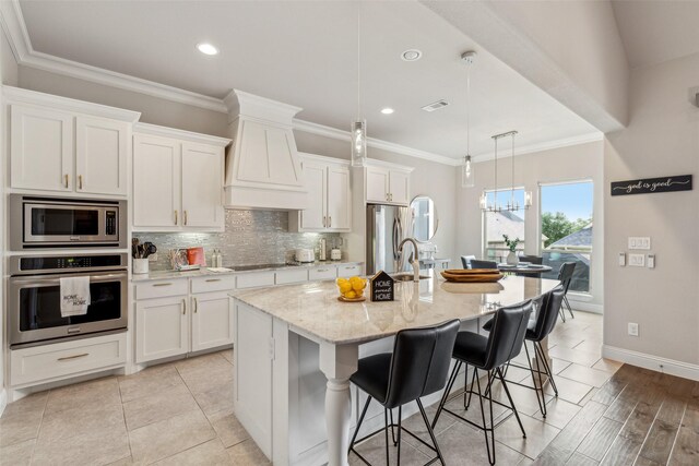 kitchen with pendant lighting, white cabinetry, an island with sink, and appliances with stainless steel finishes