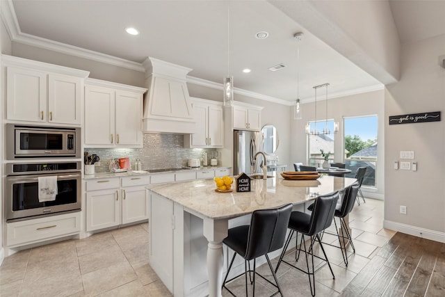 kitchen featuring white cabinetry, pendant lighting, a center island with sink, and appliances with stainless steel finishes