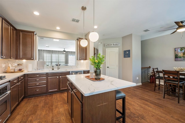 kitchen featuring appliances with stainless steel finishes, a center island, sink, hanging light fixtures, and dark hardwood / wood-style floors