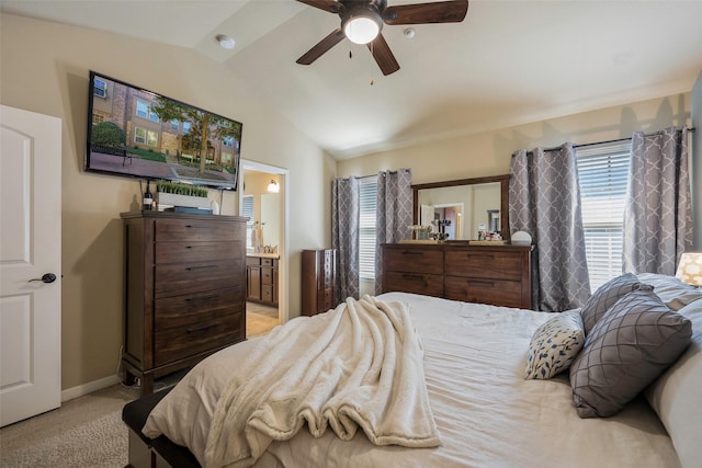 bedroom featuring ceiling fan, light colored carpet, ensuite bath, and vaulted ceiling