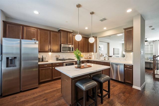 kitchen featuring a center island, stainless steel appliances, sink, hanging light fixtures, and a kitchen breakfast bar