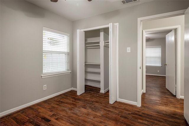 unfurnished bedroom featuring ceiling fan, a closet, and dark wood-type flooring