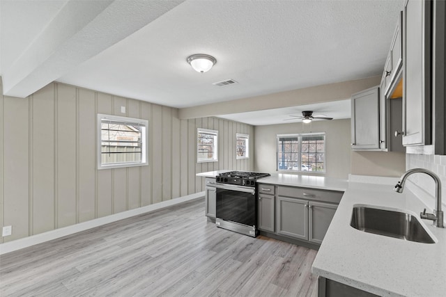 kitchen featuring stainless steel gas stove, plenty of natural light, kitchen peninsula, and sink