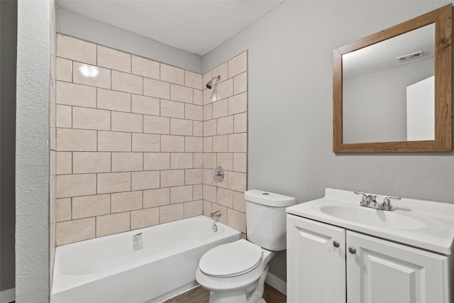 full bathroom with a textured ceiling, vanity, toilet, and tiled shower / bath