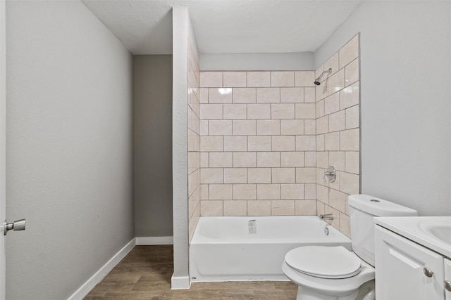 full bathroom with hardwood / wood-style floors, vanity, tiled shower / bath, toilet, and a textured ceiling