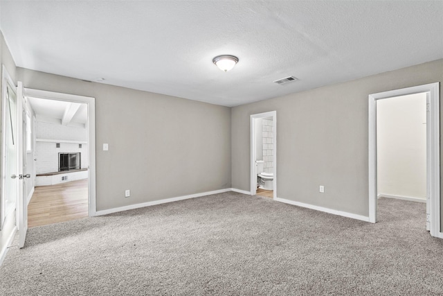 unfurnished bedroom with light carpet, a textured ceiling, and connected bathroom