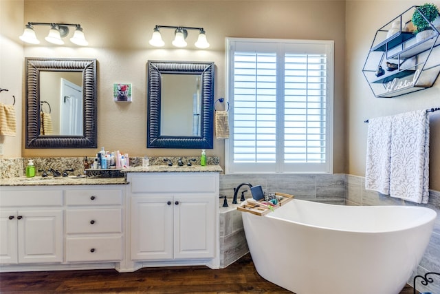 bathroom featuring vanity, wood-type flooring, and a bath