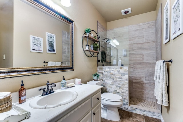 bathroom with vanity, tile patterned floors, toilet, and tiled shower