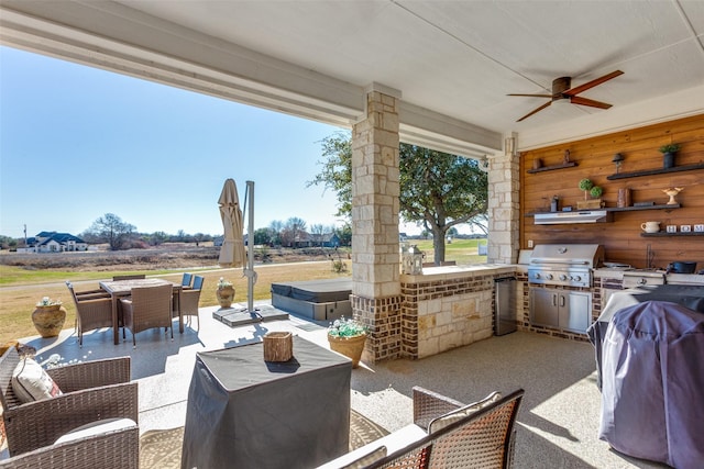 view of patio featuring ceiling fan, an outdoor kitchen, a grill, and a hot tub