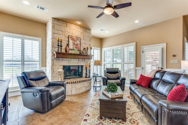 tiled living room with a fireplace, plenty of natural light, and ceiling fan