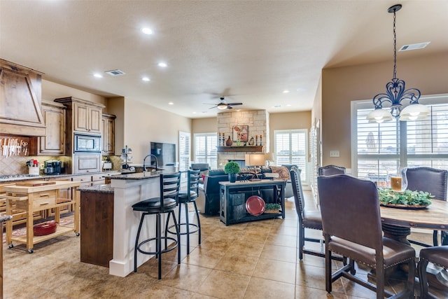 kitchen with appliances with stainless steel finishes, decorative light fixtures, dark stone countertops, a kitchen breakfast bar, and decorative backsplash