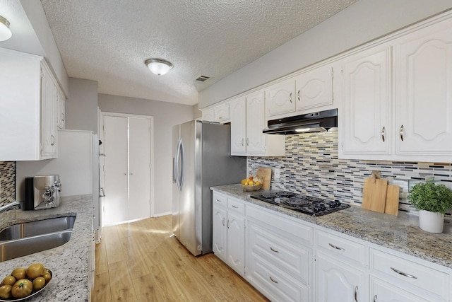 kitchen with stainless steel fridge, black gas stovetop, white cabinetry, and sink