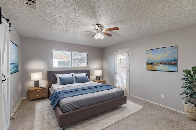 bedroom featuring ceiling fan, a barn door, light colored carpet, and a textured ceiling