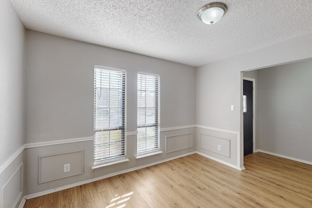 spare room featuring a textured ceiling and light wood-type flooring