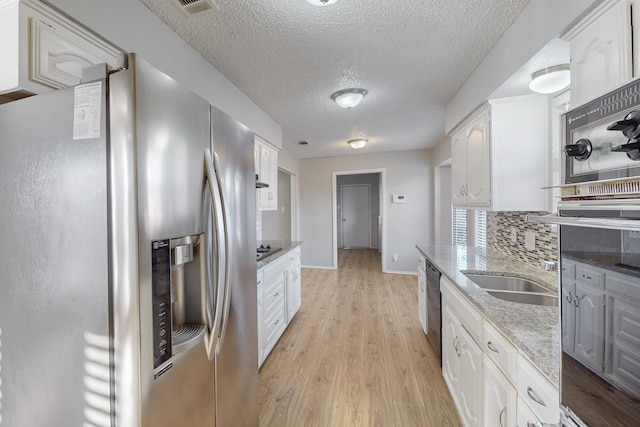 kitchen featuring decorative backsplash, light stone counters, stainless steel appliances, light hardwood / wood-style flooring, and white cabinetry