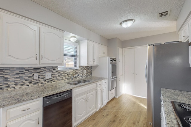 kitchen with white cabinets, sink, light stone countertops, tasteful backsplash, and stainless steel appliances