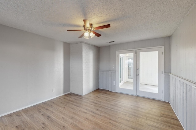 unfurnished room with light wood-type flooring, french doors, a textured ceiling, and ceiling fan