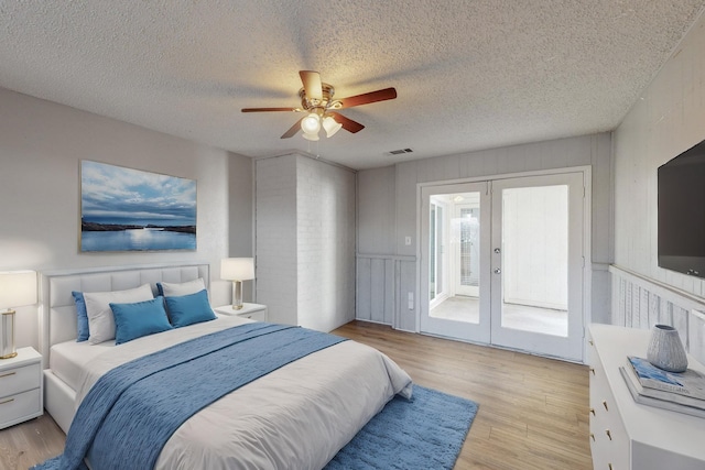 bedroom with ceiling fan, french doors, light hardwood / wood-style flooring, a textured ceiling, and access to outside