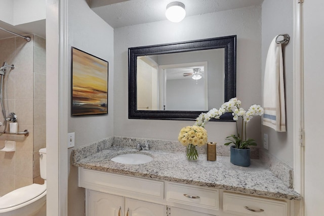 bathroom featuring tiled shower, vanity, and toilet