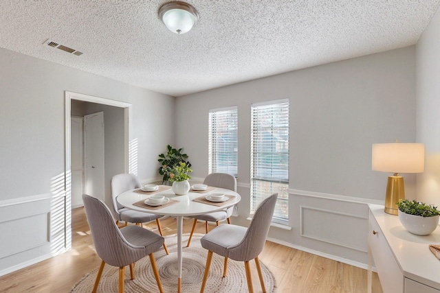 dining room with a textured ceiling and light wood-type flooring