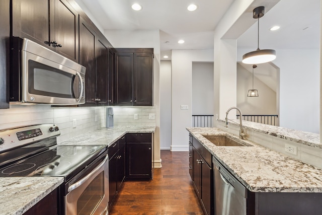 kitchen with light stone countertops, sink, dark wood-type flooring, decorative light fixtures, and appliances with stainless steel finishes