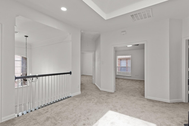 spare room featuring light carpet, plenty of natural light, visible vents, and attic access