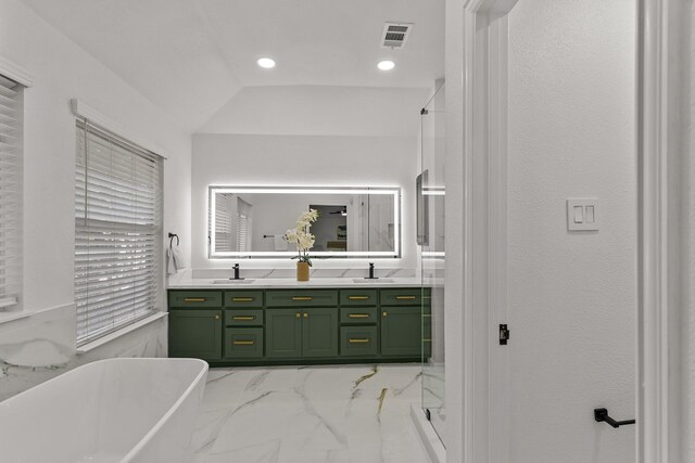 full bathroom featuring a freestanding bath, marble finish floor, double vanity, and a sink