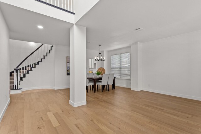 dining room featuring light wood-type flooring, an inviting chandelier, and crown molding