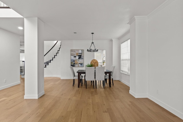 dining room with light wood-type flooring, stairs, baseboards, and crown molding