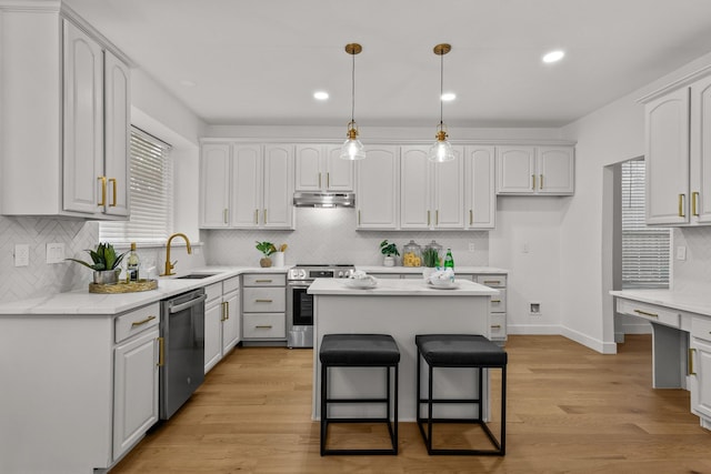 kitchen with under cabinet range hood, stainless steel appliances, a sink, a kitchen island, and white cabinetry