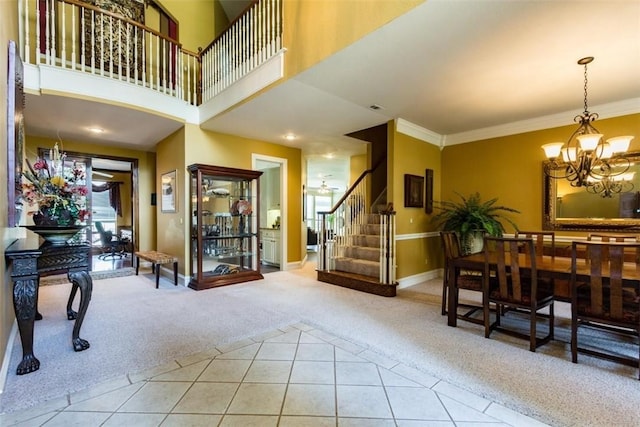 foyer with ornamental molding, a chandelier, carpet, and a high ceiling