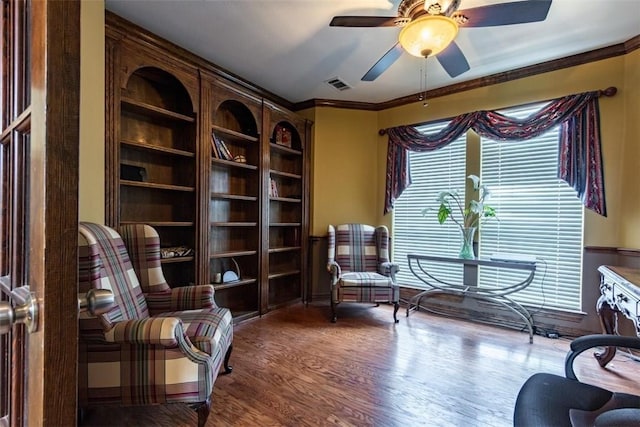 sitting room featuring hardwood / wood-style flooring, ornamental molding, built in shelves, and ceiling fan