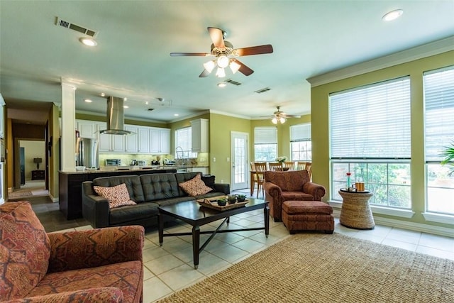 living room with light tile patterned floors, ornamental molding, decorative columns, and ceiling fan