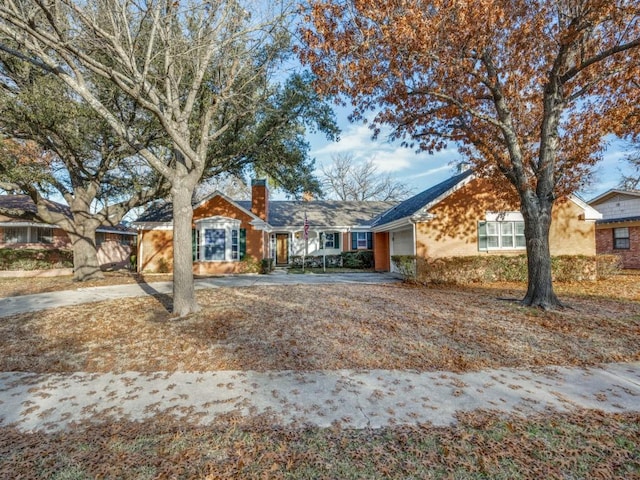 ranch-style home featuring concrete driveway, a chimney, and an attached garage