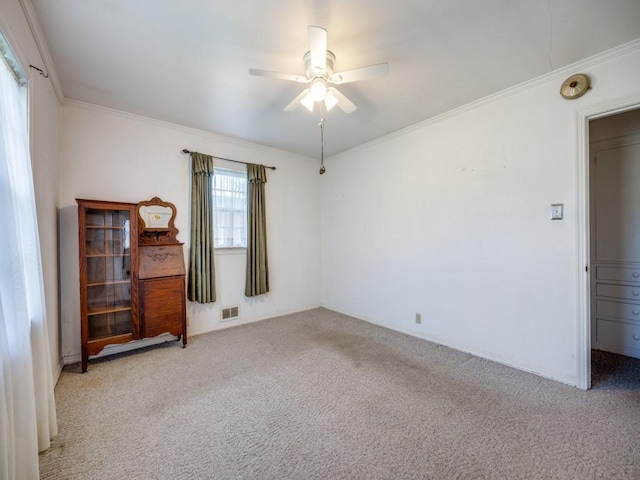 unfurnished room featuring ceiling fan, light colored carpet, visible vents, and crown molding