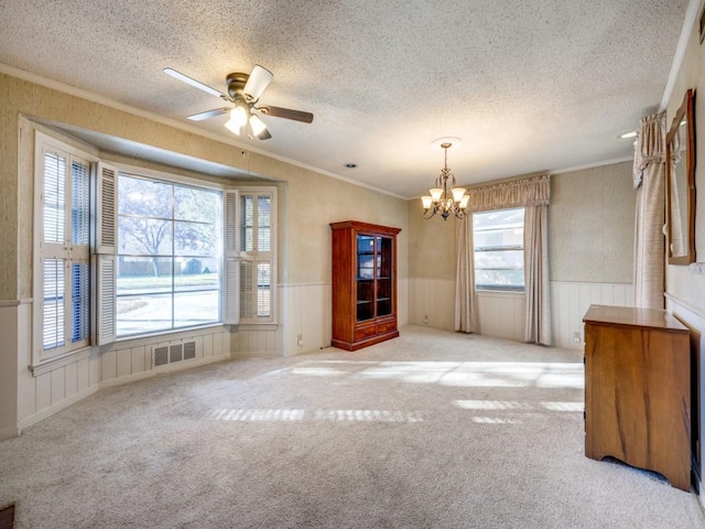 spare room featuring visible vents, ornamental molding, a textured ceiling, and wainscoting